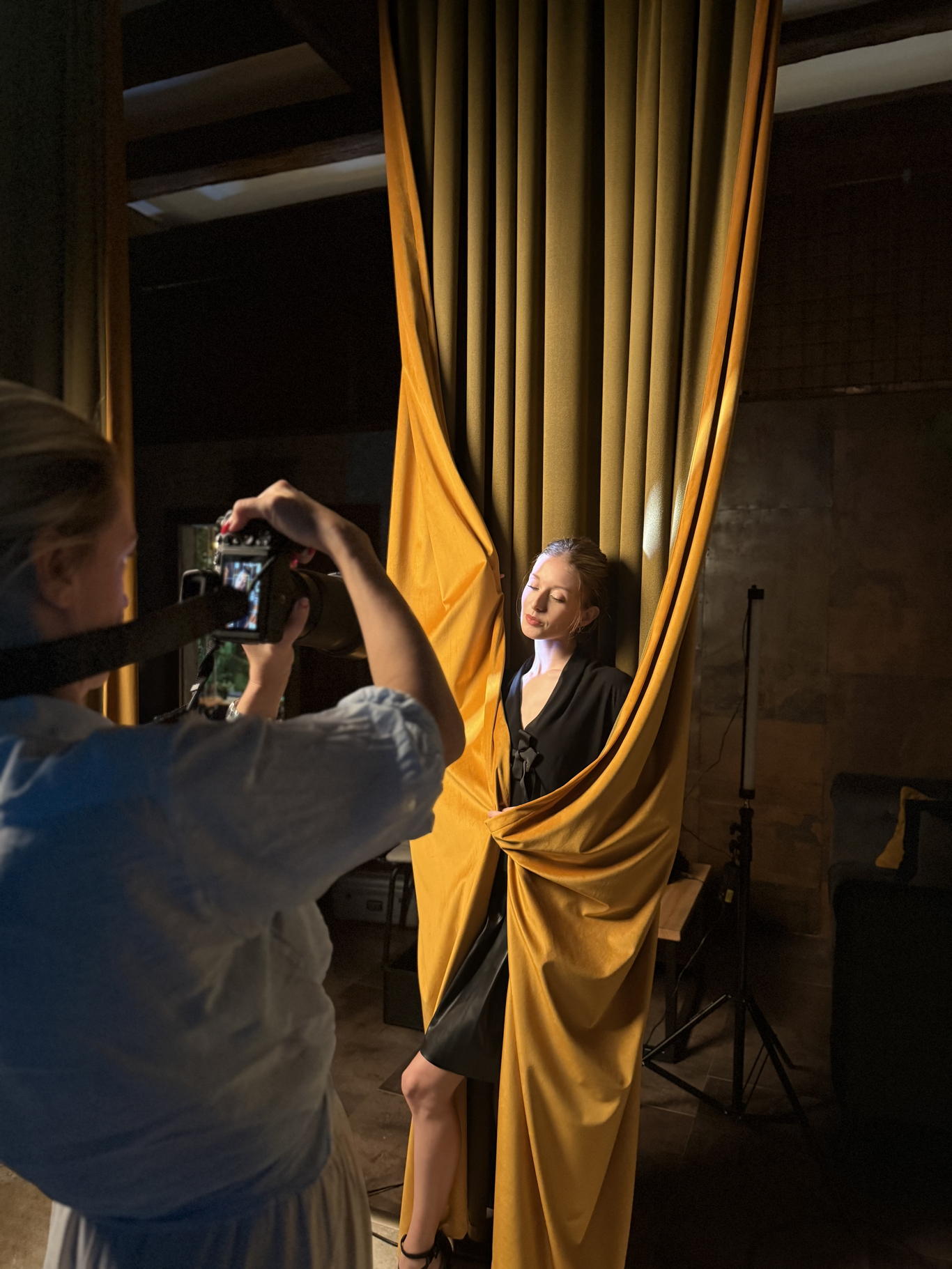 Workshop v Curtain Space — účastnice fotí modelku zahalenou ve zlatém závěsu