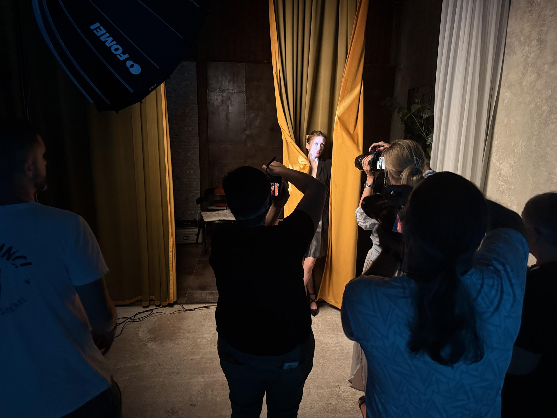 Skupina účastníků workshopu fotí v Curtain Space pod softboxy Fomei
