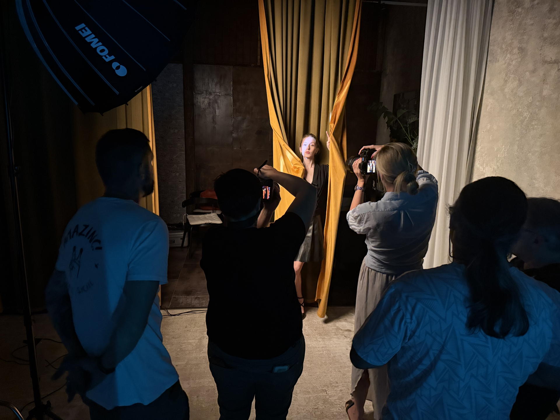 Workshop portrétového svícení v Curtain Space — účastníci a modelka mezi závěsy