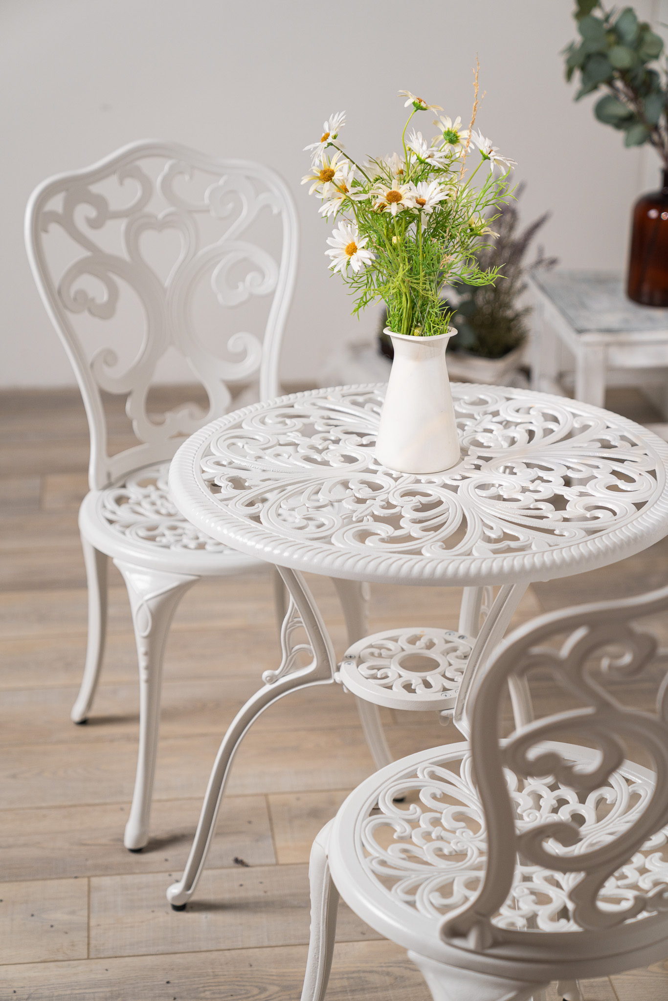 Detail scény Hygge Corner — ornamentální kovaný stolek s kopretinami